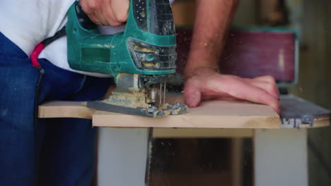 man using a jigsaw to cut wood