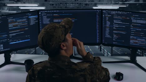 back view of tired asian military yawning while write code with multiple computer screens in data center