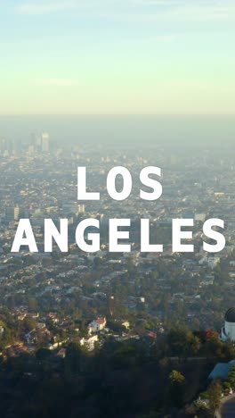 vertical video aerial drone shot of city buildings and skyline in america overlaid with animated graphic spelling out los angeles