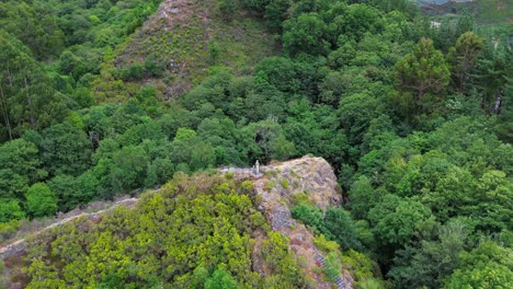 hiker standing on a narrow path surrounded by dense forest in galicia, spain, aerial view