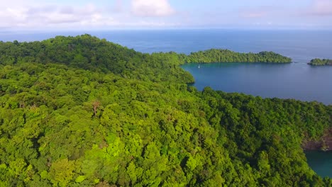 Aéreo-Sobre-Una-Densa-Isla-Tropical-Verde-Con-Calas-De-Agua-Azul