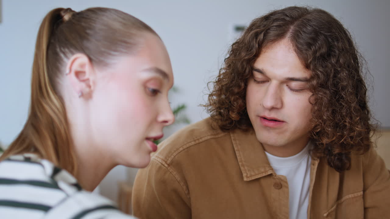 Young husband eating raspberry in bright kitchen talking to beloved wife closeup