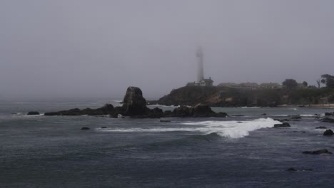 Un-Faro-Costero-En-La-Niebla-Con-Olas-Rompiendo-En-Primer-Plano