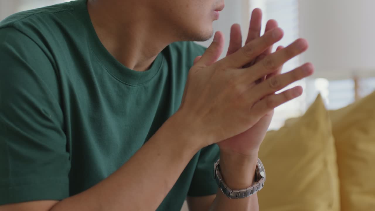 소파에 앉아 있는 아시아인 남자가 집에서 멀리 쳐다보며 생각나는 피로를 느다.