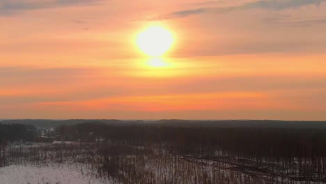 colorful pink sunrise in winter over leafless trees, aerial dolly out