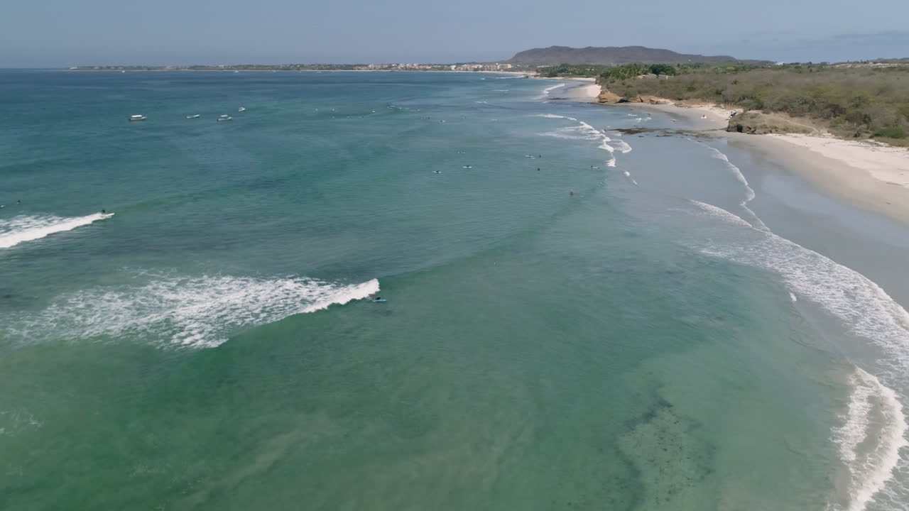 antena en órbita mientras un surfista atrapa una ola en la hermosa costa azul del pacífico, 4k