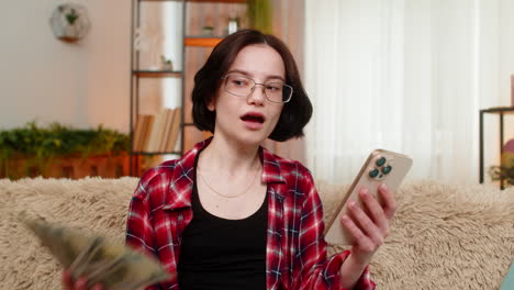happy woman celebrating money win on smartphone raising arms after hitting jackpot in online lottery
