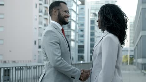 smiling man and woman shaking hands on street