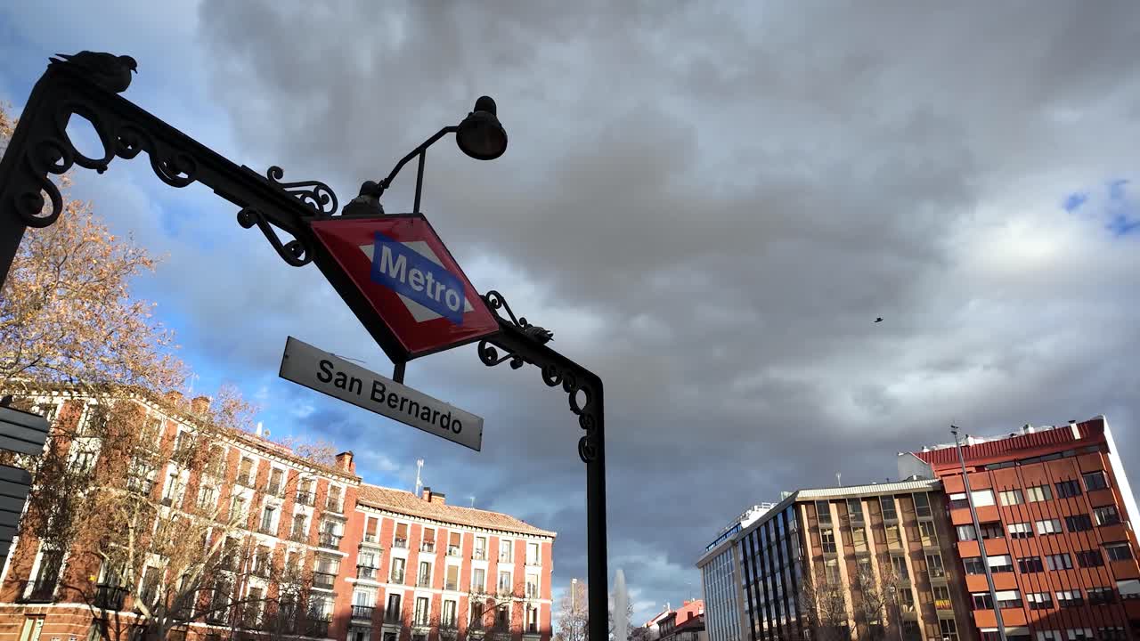 Static shot of the entrance to San Bernardo Metro station in the Chamberí neighborhood of Madrid, Spain, with clouds starting to gather in the sky