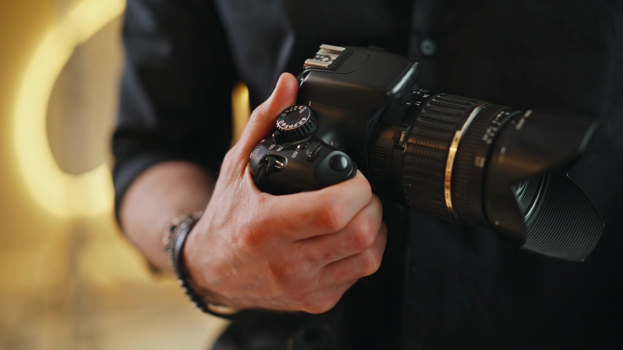 Zbliżenie dłoni fotografa regulującego pokrętło ustawień aparatu DSLR w studiu.