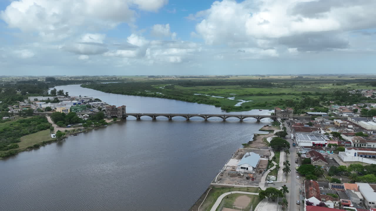Ripresa cinematografica lunga in allontanamento e inquadratura rivelatrice di addio che mostra lo storico Ponte Internazionale Mauá sul fiume Jaguarão, al confine tra Brasile e Uruguay