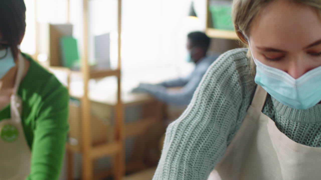 mujer con máscara y guantes empaquetando cajas de alimentos orgánicos en una bolsa de entrega