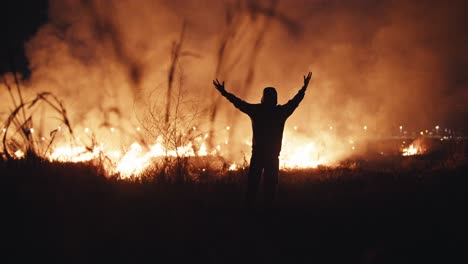 person standing amidst a raging wildfire at night