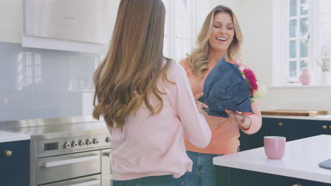 hija adolescente con flores detrás de la espalda como regalo para la madre en el día de la madre o cumpleaños