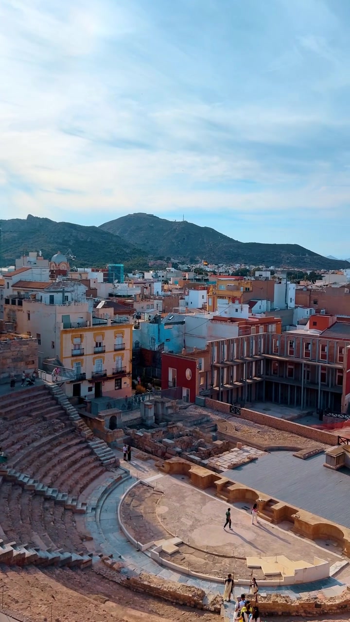 Alicante, Spanien, 9. august 2025: Det antikke romerske teater i Cartagena med bybillede og bjerge. Forhøjet udsigt over det romerske teater i Cartagena, Spanien