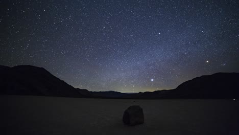 stationary time lapse of the milky way and stars over a moving rock on the racetrack playa