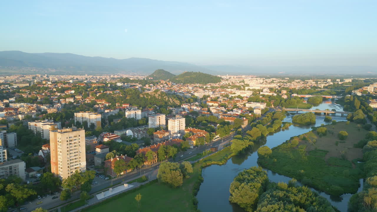 Aerial view of Plovdiv and the Maritsa River at sunrise in early spring. Lush greenery, bridges and cityscape unfold in soft golden light
