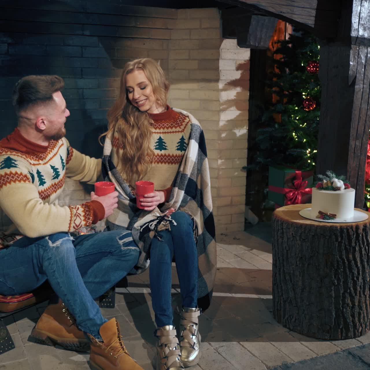 Loving couple warming in the evening near fireplace. Same knitted sweaters on male and female