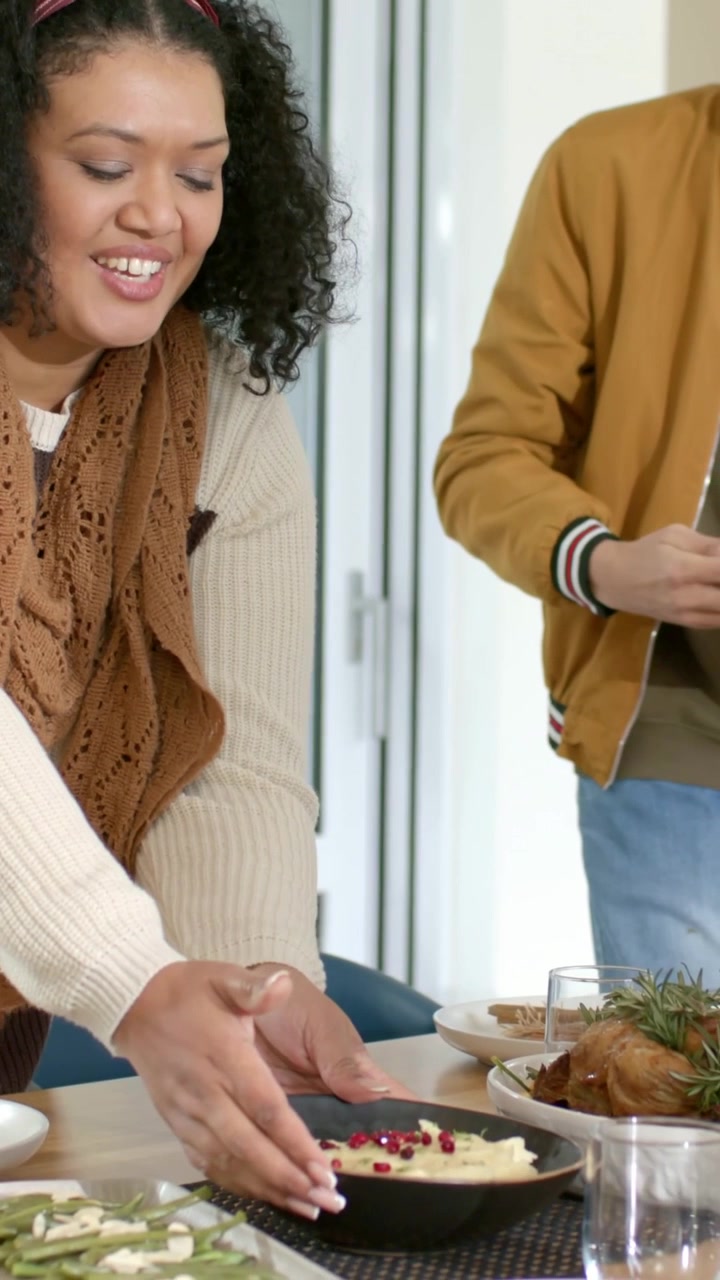 Vertical video: Entering woman in scarf holding black bowl seeded placing on table for meal at home
