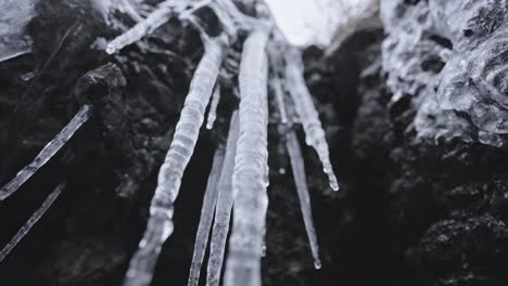 Eiszapfen,-Die-Von-Felsvorsprüngen-Hängen,-Deuten-Aus-Der-Nähe-Auf-Die-Kälte-Des-Winters-Hin