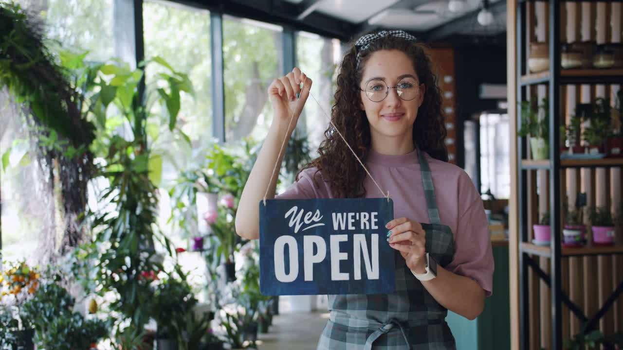 Woman Holding Open Sign in a Floral Shop