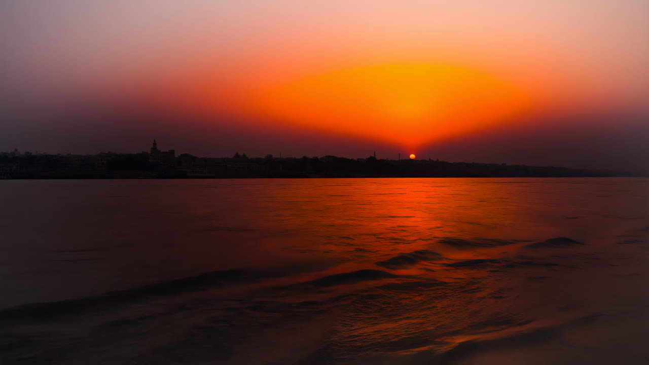 Vibrant Sunset over a River with City Silhouette