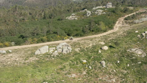 ciclistas de montaña deslizándose rápidamente por un camino de tierra en alto minho, portugal - toma aérea de seguimiento de órbita amplia