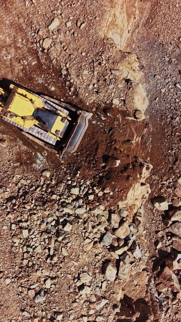 Excavator working on rocky terrain in construction site during daytime