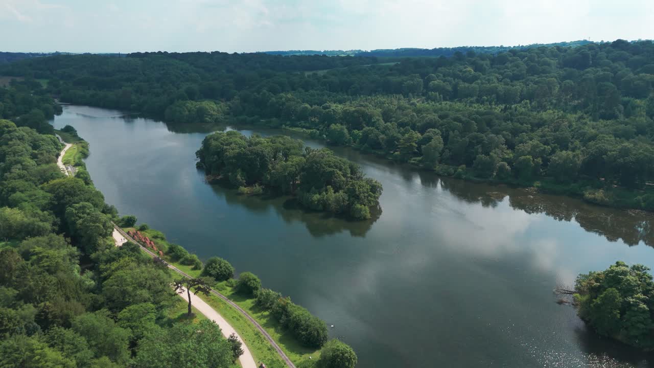 Una vista maestosa del lungo lago di Trentham con una piccola isola al centro ricoperta di alberi.