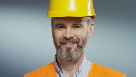 portrait shot of the joyful male builder and architect in the yellow casque smiling to the camera happily