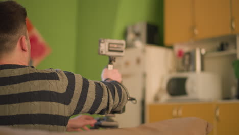 tv technician working with studio equipment, adjusting settings on camera tripod, shot from behind. focus on technician's hands and back, with kitchen setting in background