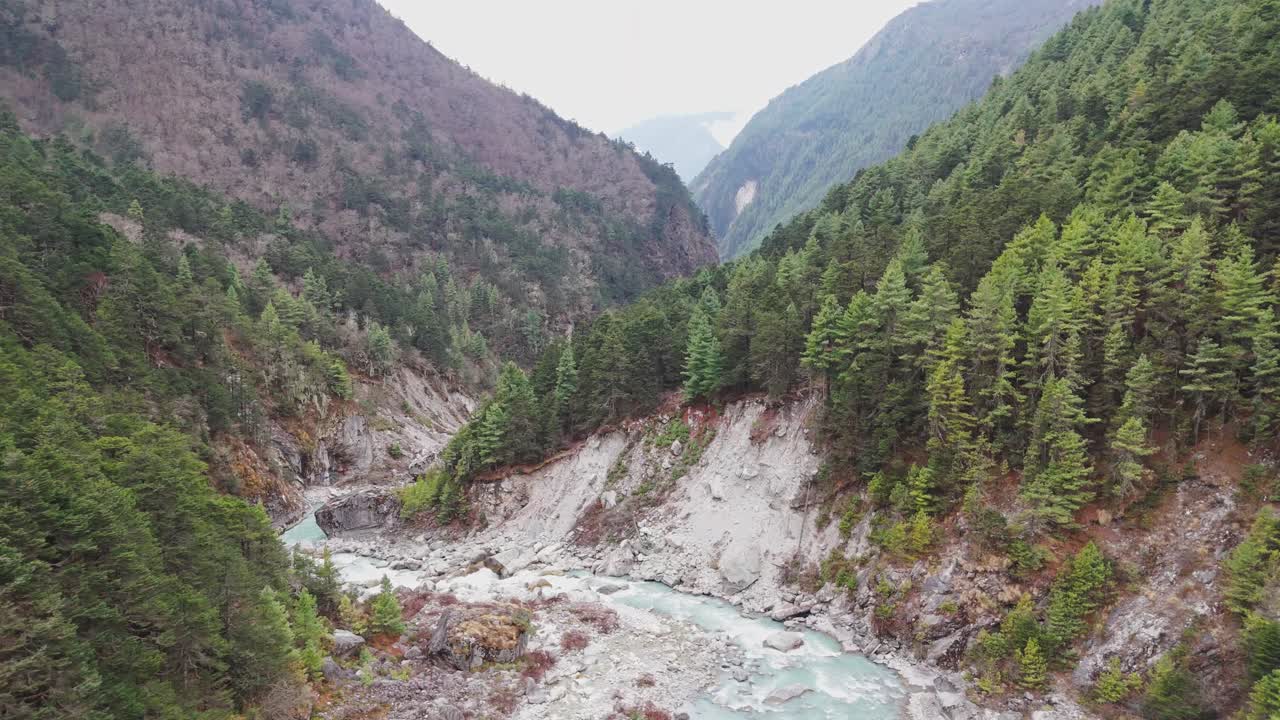 A pristine Himalayan river winds through vibrant green mountains, offering a peaceful and refreshing view of untouched nature.
