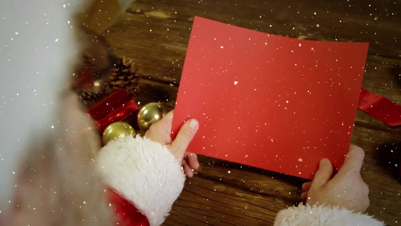 composición de video con nieve cayendo sobre el escritorio con santa con tarjeta roja