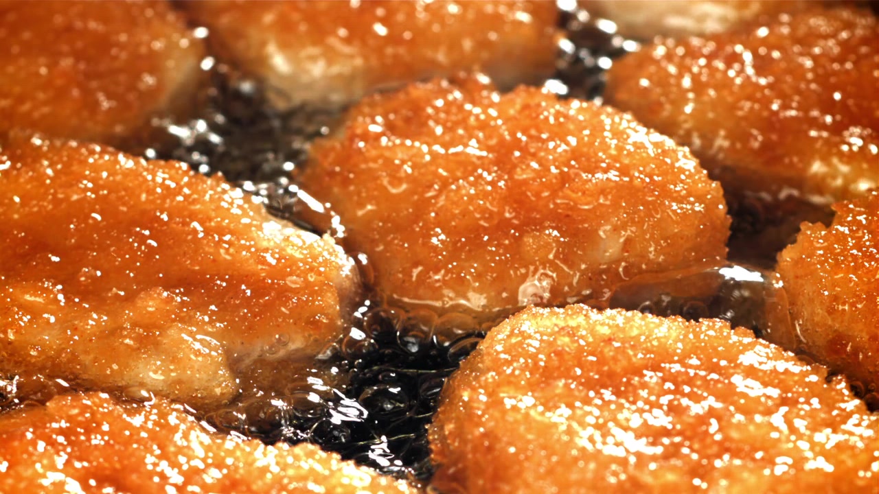 熱い油で揚がる黄金色のチキンナゲットのクローズアップ