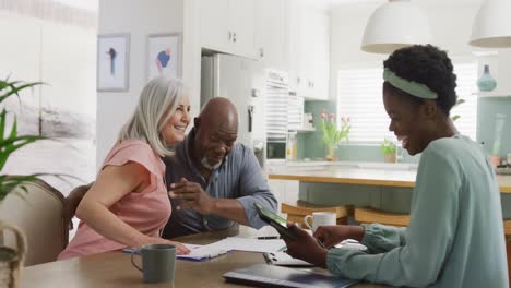 Happy-senior-diverse-couple-with-african-american-female-friend-talking-about-work