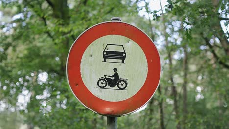 prohibition traffic sign for cars an scooters in a green belgian forest landscape