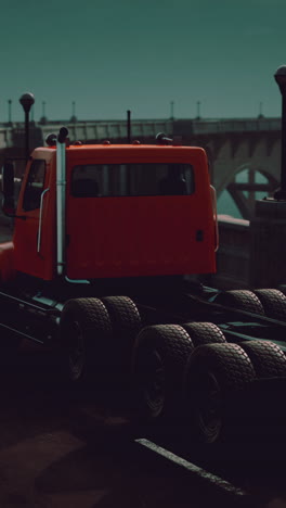 orange semi-truck driving on a highway bridge