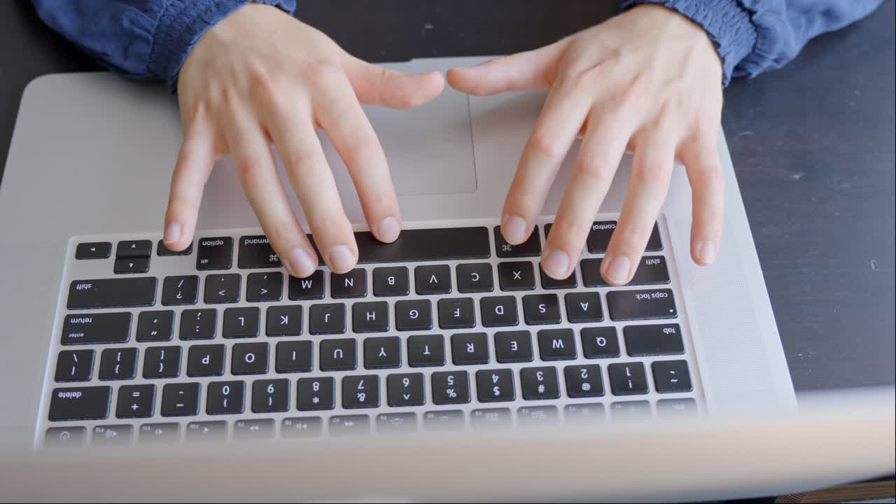 manos femeninas de escribir en el teclado de la computadora portátil en el escritorio de casa, vista superior
