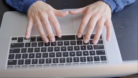 female hands of typing on laptop keyboard at home desk, above view