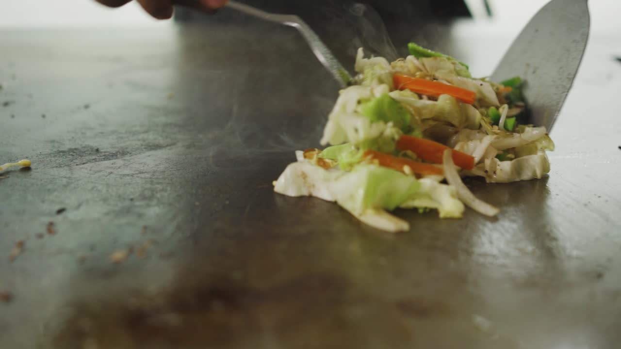 teppanyaki - cocinar verduras a la plancha con una espátula de metal