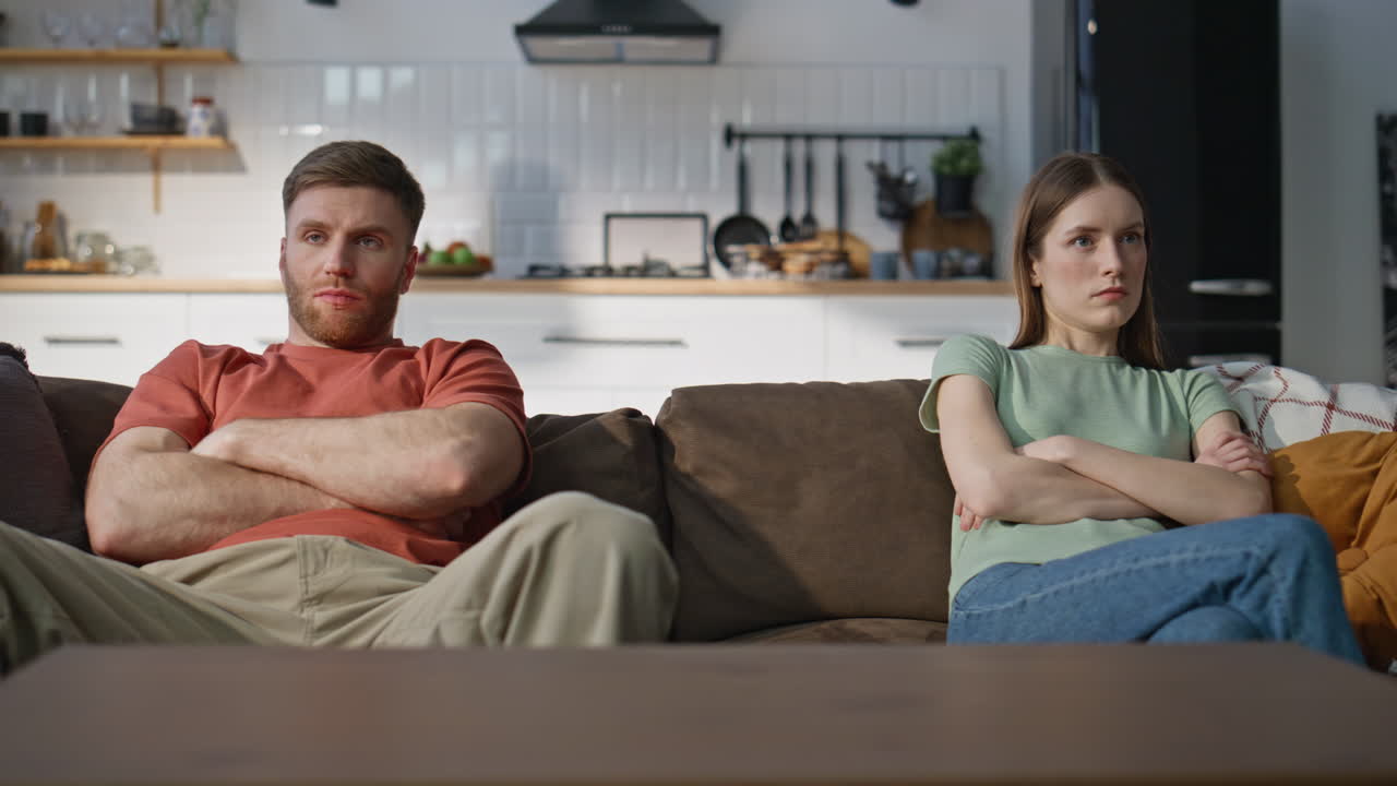 Angry spouses sitting couch separately showing frustration closeup. Unhappy wife
