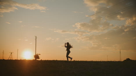 silhouette of a person walking through a field at sunset