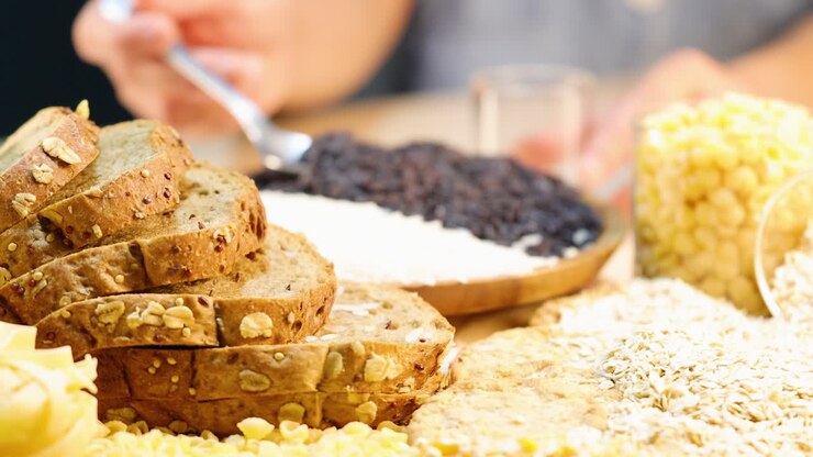 A close-up of whole grain bread, pasta, and grains being prepared in a well-lit kitchen setting