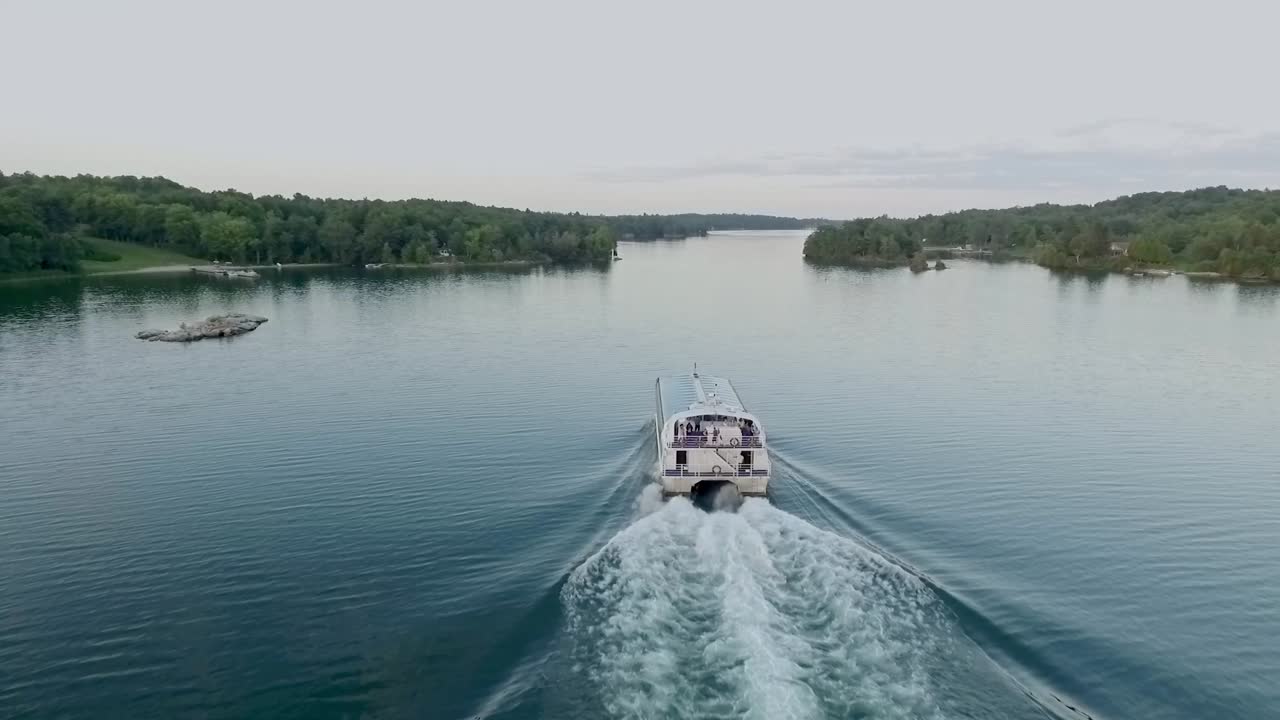 Glass topped boat cruises on a river with people onboard holding a Canadian flag