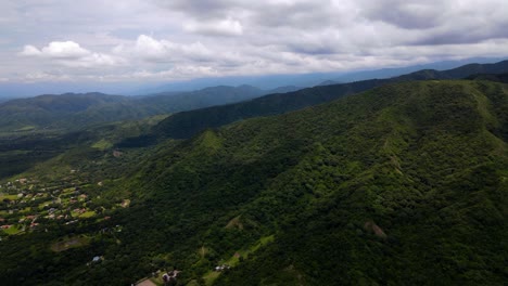 drone shot flying towards forest covered mountains near the city of salta, argentina