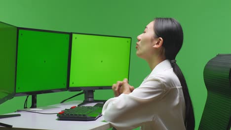 woman working at computer with green screen monitors