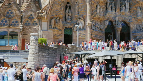 many tourists walk and take pictures at the entrance to the church of the sagrada familia in barcelo