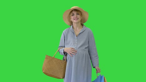 happy pregnant woman in summer clothes walking with shopping bags on a green screen, chroma key