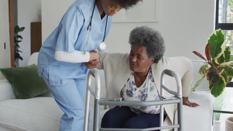 caring african american female doctor helping senior african american female