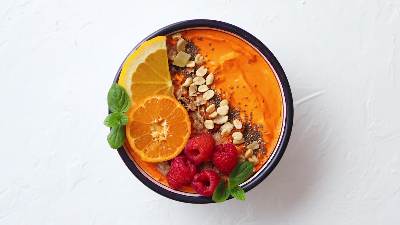 tazón con batido fresco y saludable o yogur con rodajas de naranja, mandarina, frambuesa, chía y nueces